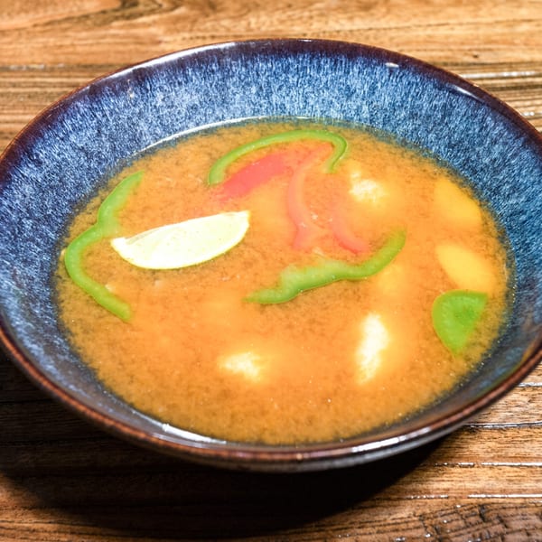 Kiwami Ramen Sushi's miso soup with green peppers, red peppers, and a lemon slice.