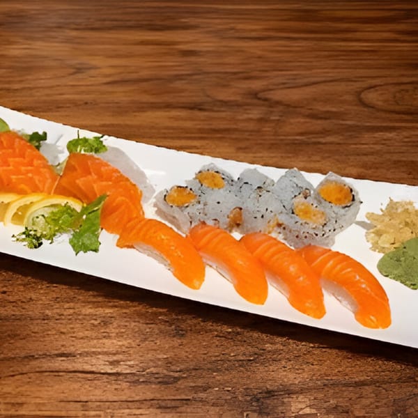 A white platter of salmon sashimi, salmon nigiri, and sushi rolls with wasabi and ginger.
