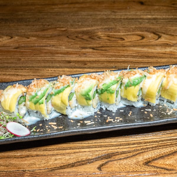 Kiwami Ramen Sushi's avocado and mango sushi roll, drizzled with white sauce and topped with flakes.