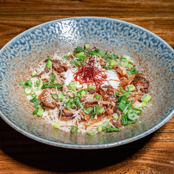Kiwami Ramen Sushi's Japanese dish with meat, rice, green onions, and a dollop of cream.