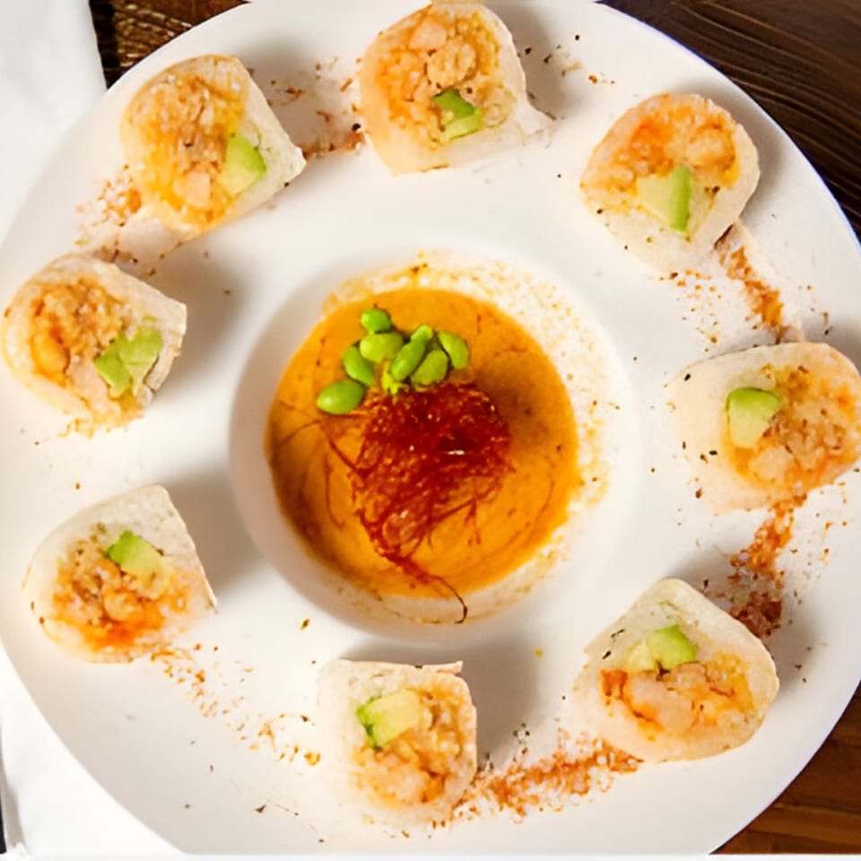 Eight pieces of Kiwami Ramen Sushi's shrimp and avocado sushi rolls surround a dipping sauce.