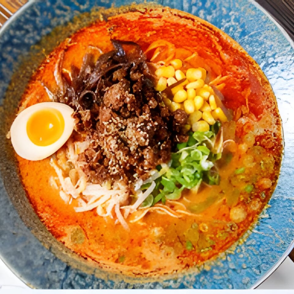 Spicy ramen bowl from Kiwami Ramen Sushi, topped with ground meat, corn, egg, and greens.