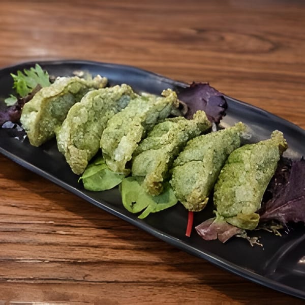 Six green fried gyoza dumplings with lettuce on a black rectangular plate at Kiwami Ramen Sushi.